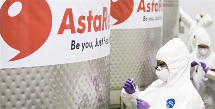 AstaReal cultivation facility with technicians in cleanroom suits beside stainless bioreactors