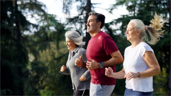 Three older adults jogging together outdoors